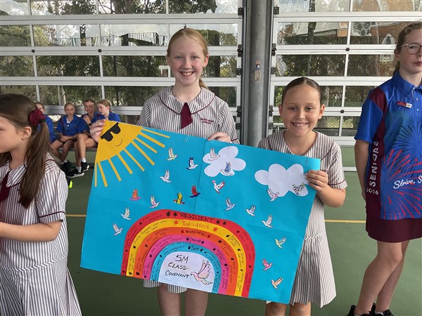 Two students holding a class covenant poster